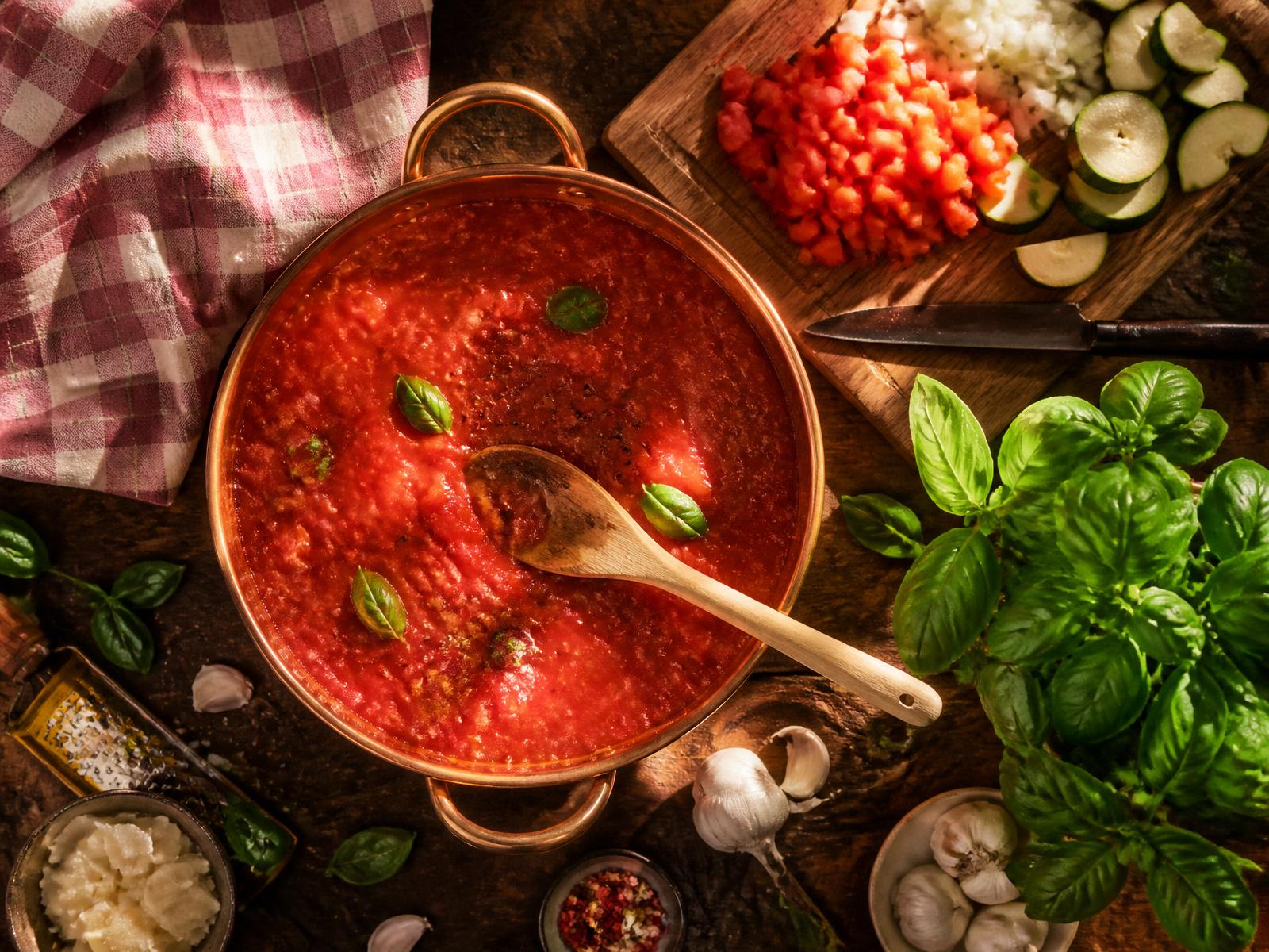 Overhead shot of a bubbling pot of tomato sauce with fresh basil